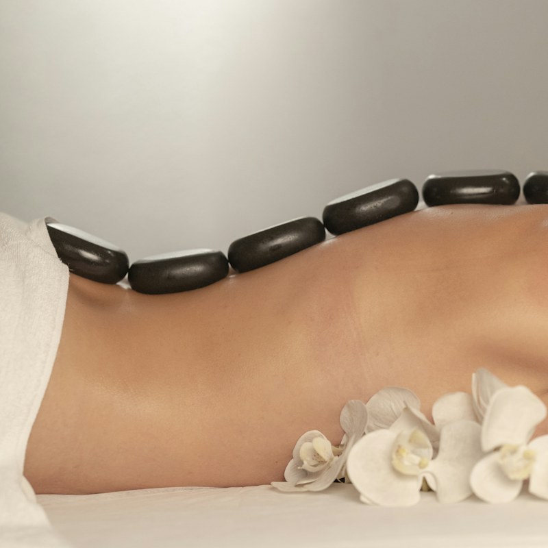 Hot stone massage with warm stones along the spine